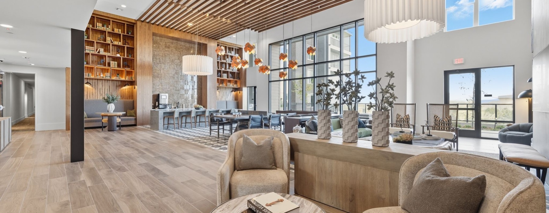 Modern apartment lounge with elegant wood accents, cozy seating, and floor-to-ceiling windows offering natural light at The Aven