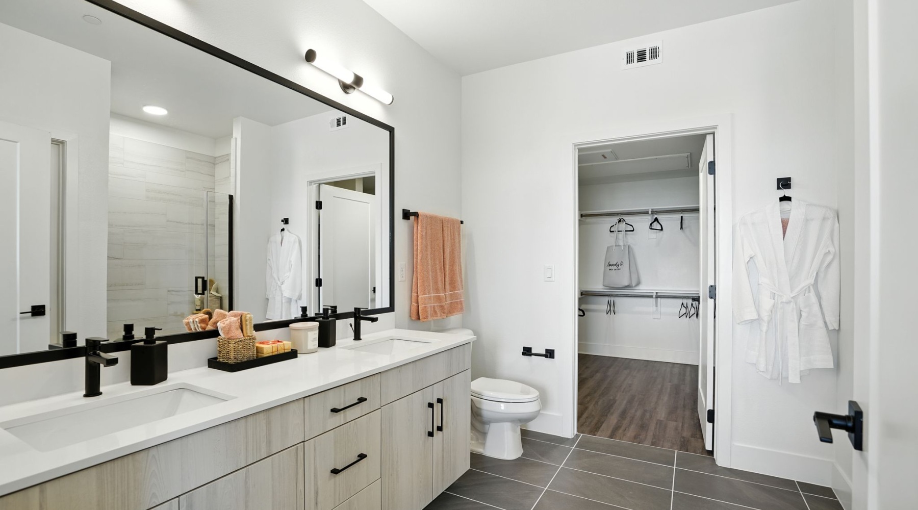 Refresh and recharge in sleek surroundings Luxurious bathroom with double sinks, elegant lighting, and spacious walk-in closet in a modern apartment at The Aven in Colorado Springs