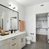 Luxurious bathroom with double sinks, elegant lighting, and spacious walk-in closet in a modern apartment at The Aven in Colorado Springs