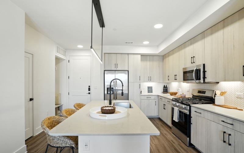 Modern kitchen with sleek granite countertops, stainless steel appliances, and stylish cabinetry complementing a warm, open layout at The Aven in Colorado Springs